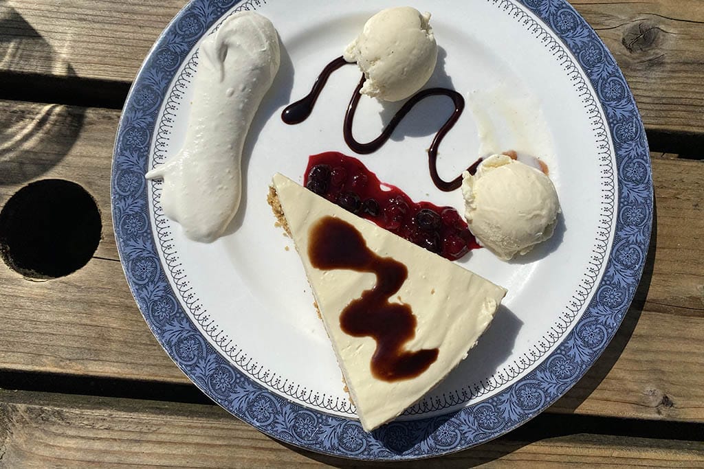 Vanilla cheesecake with ice cream, whipped cream, fruit compote and chocolate sauce